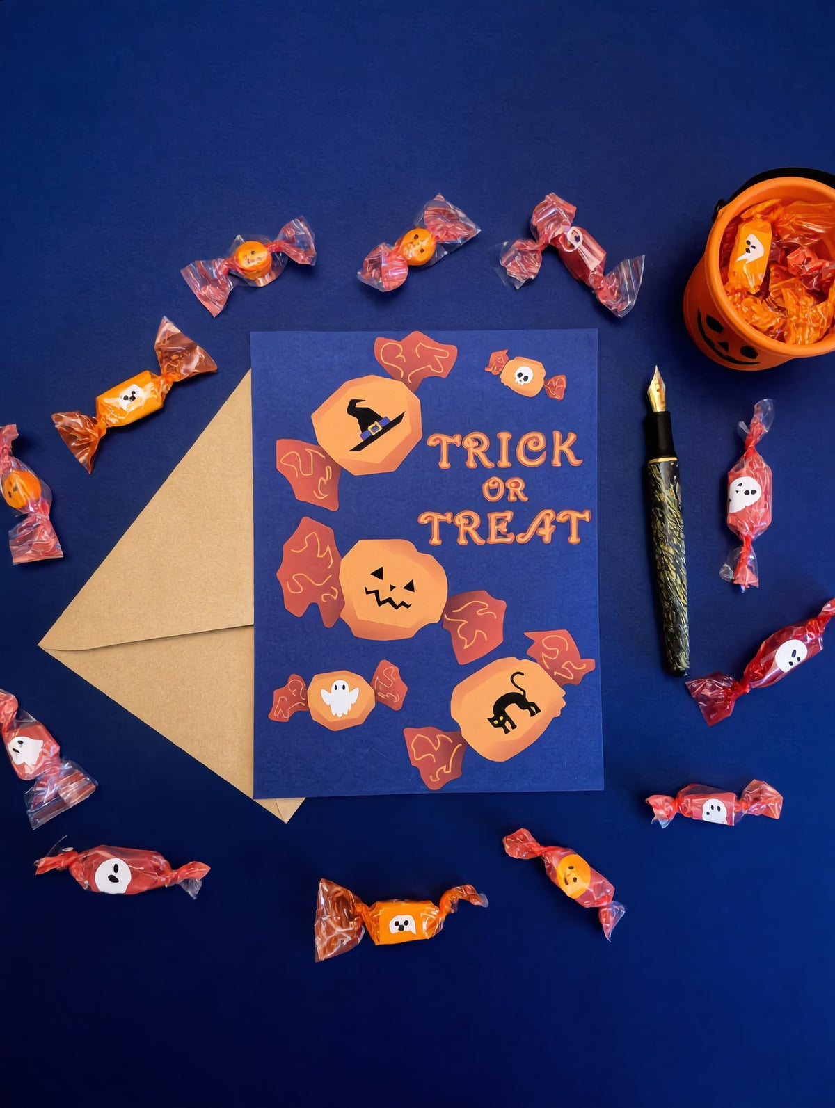 Halloweenkortti Trick or Treat sinisellä pohjalla karkkien, kirjekuoren ja täytekynän kanssa